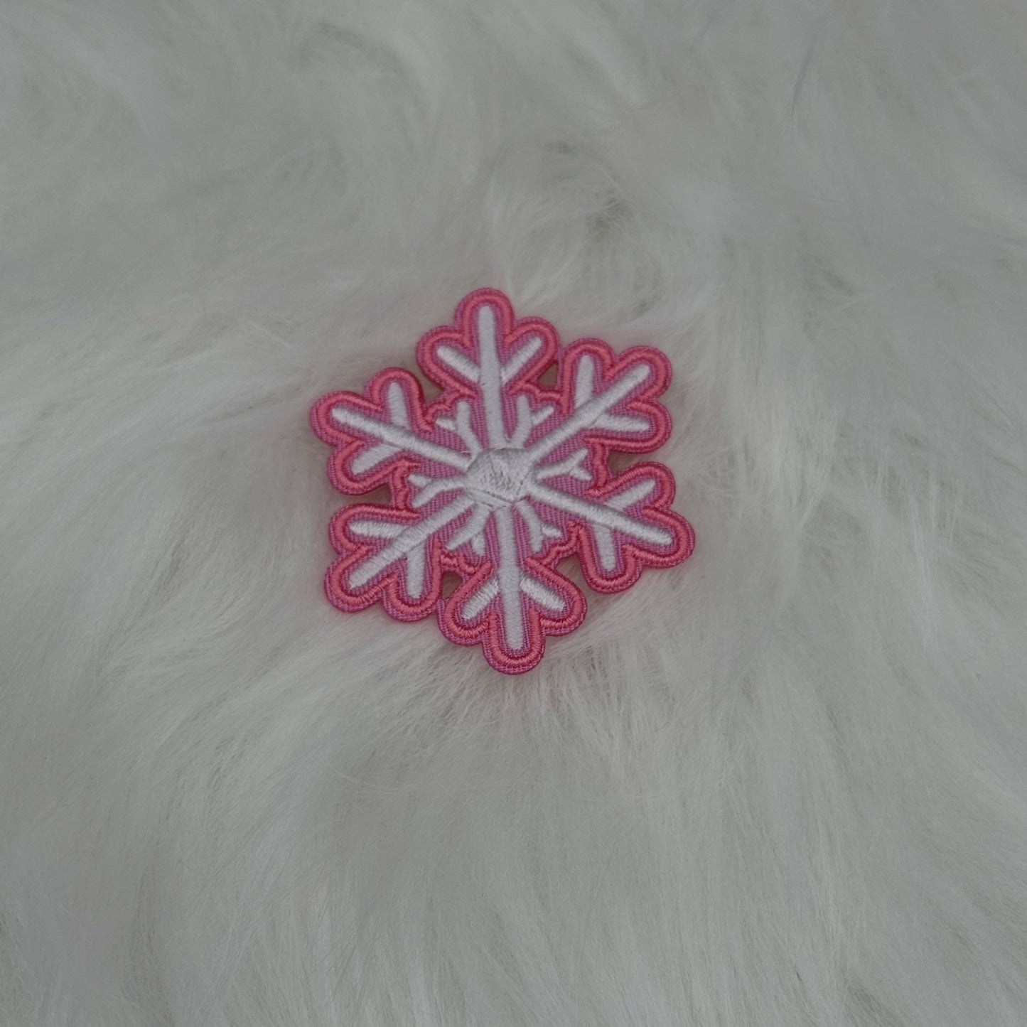 Pink and white snowflake patch on a white fur background.

The patch is embroidered. The patch colors are pink and white. This is displayed on a fluffy white fur blanket. 

Great for winter and après ski clothing, bags, accessories and gifts!