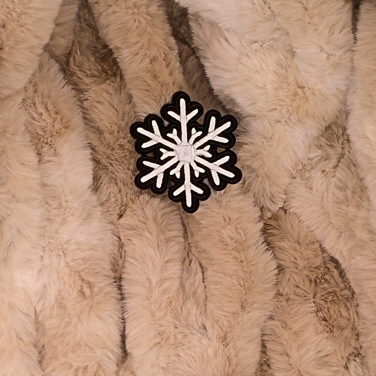 Brown and white snowflake patch on a beige fur background.

The patch is embroidered. The patch colors are Brown and white. This is displayed on a fluffy brown fur blanket. 

Great for winter and après ski clothing, bags, accessories and gifts!