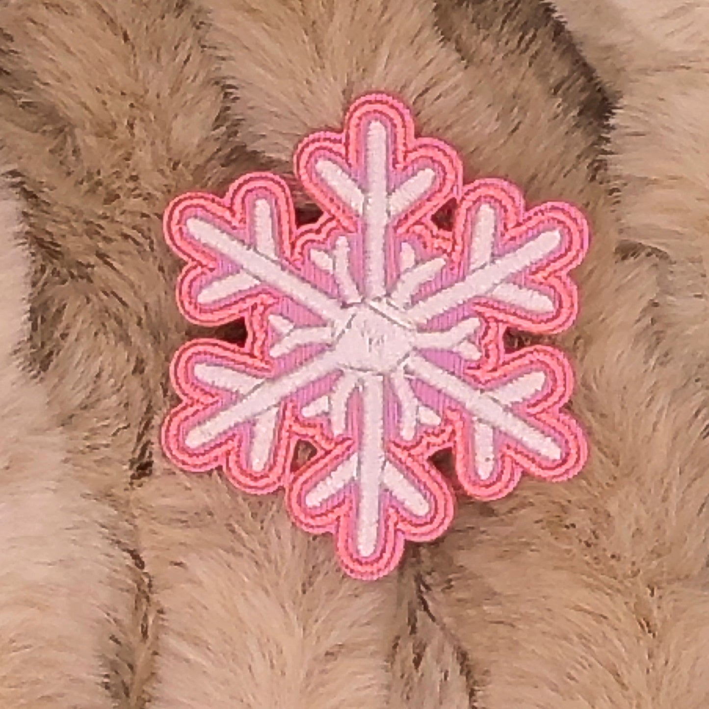 Pink and white snowflake patch on a beige fur background.

The patch is embroidered. The patch colors are pink and white. This is displayed on a fluffy brown fur blanket. 

Great for winter and après ski clothing, bags, accessories and gifts!