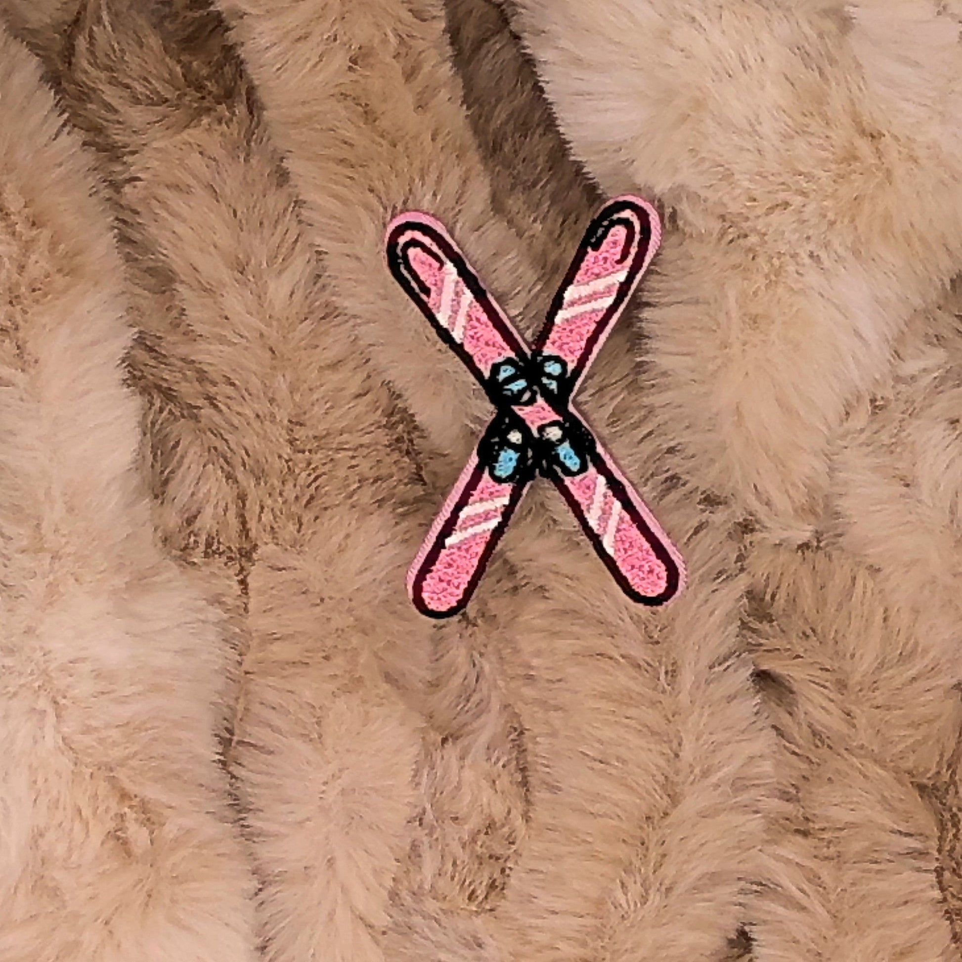 Pink and white crossed ski embroidered patch on a beige fur background

The patch is embroidered. The patch colors are pink and white with pale blue bindings. This is displayed on a fluffy brown fur blanket. 

Great for winter and après ski clothing, bags, accessories and gifts!