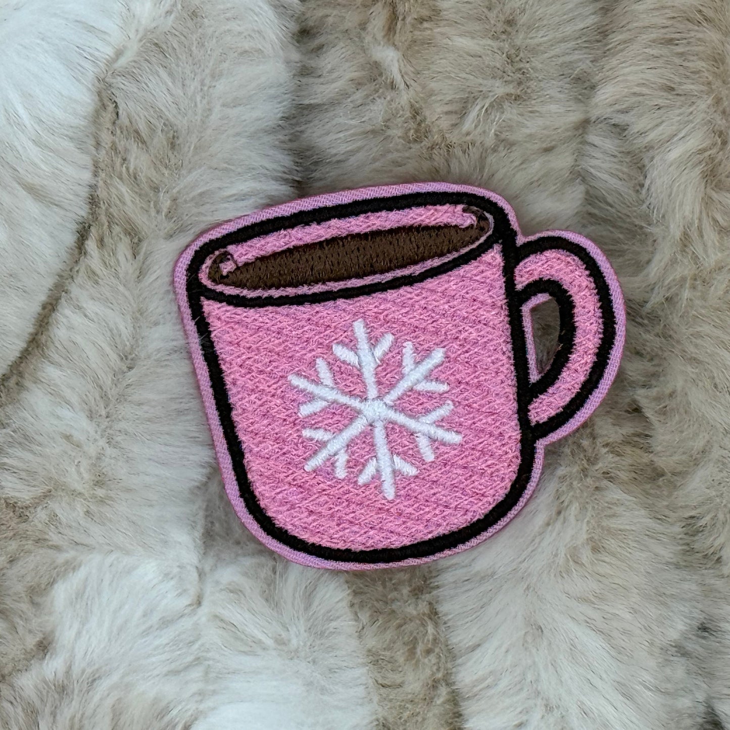 Pink and white cocoa mug embroidered patch on a beige fur background

The patch is embroidered. The patch colors are pink and white for the mug with brown hot cocoa inside the mug. This is displayed on a fluffy brown fur blanket. The mug is pink with a white snowflake on it.

Great for winter and après ski clothing, bags, accessories and gifts!